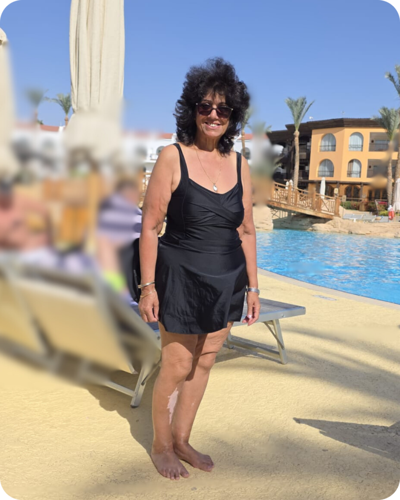 Woman smiling in black swimwear next to a swimming pool
