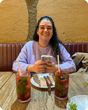 Image of women with dark hair sitting in cafe with two drinks on the table