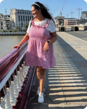 Image of woman wearing a pink dress and white t shirt on a bridge