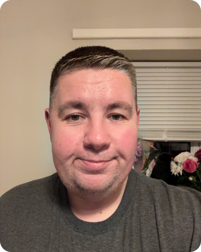 Man with short brown hair smiling to camera